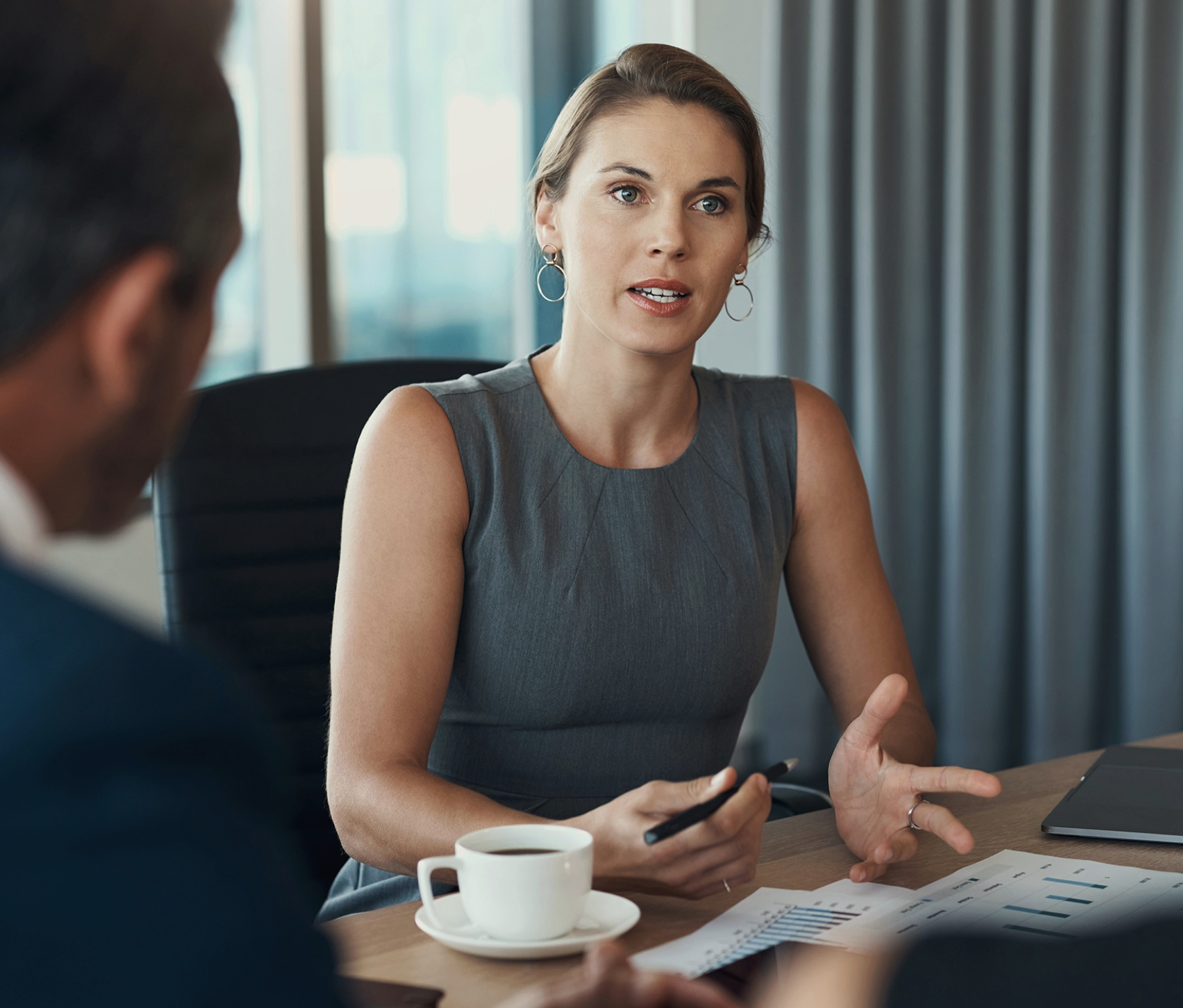 Woman talking in a meeting holding a pen with charts.