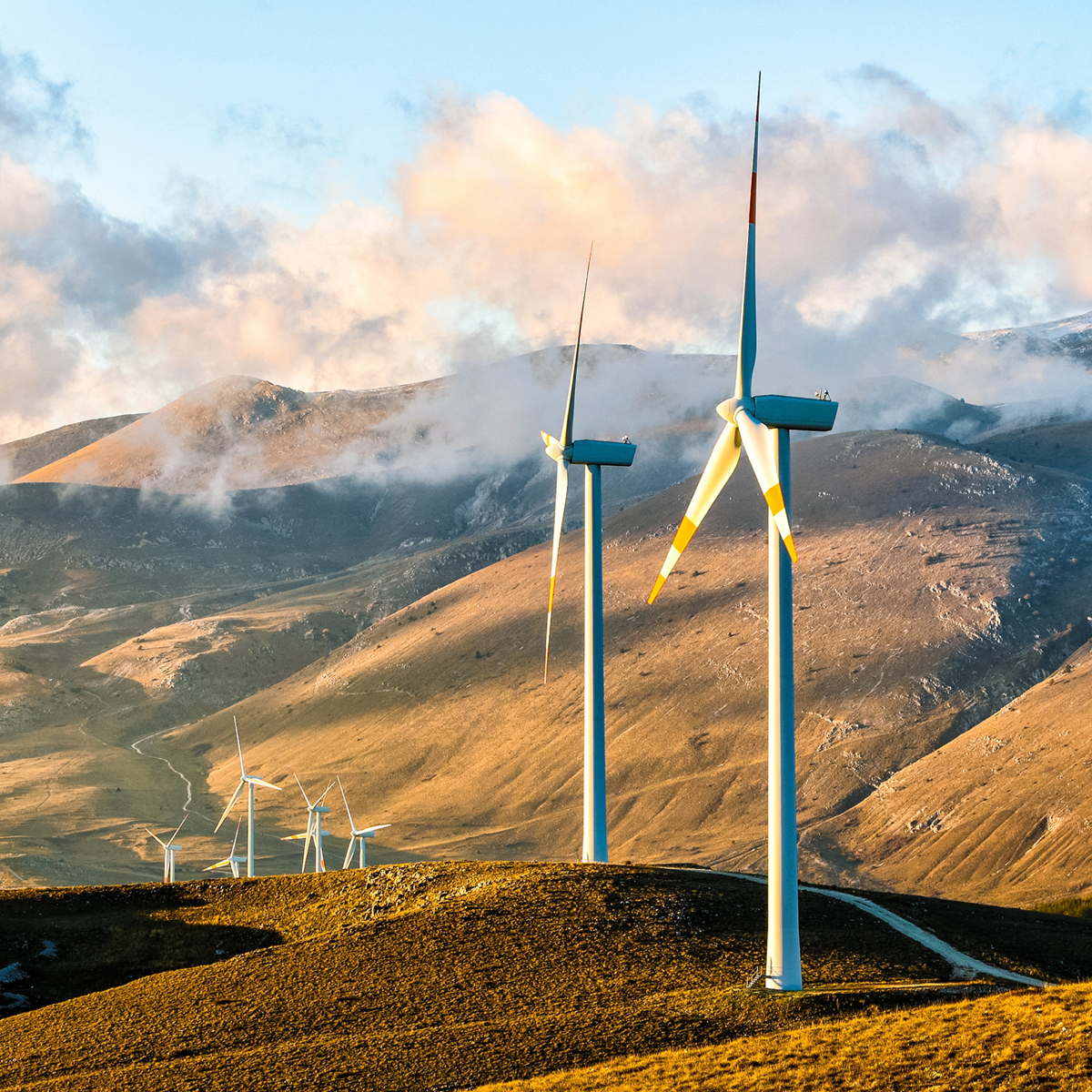 Wind turbines in hills with clouds over hills.